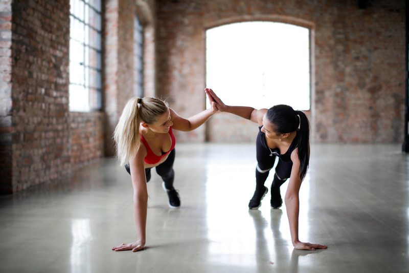 Canva - Young slender female athletes giving high five to each other while training together in sports club